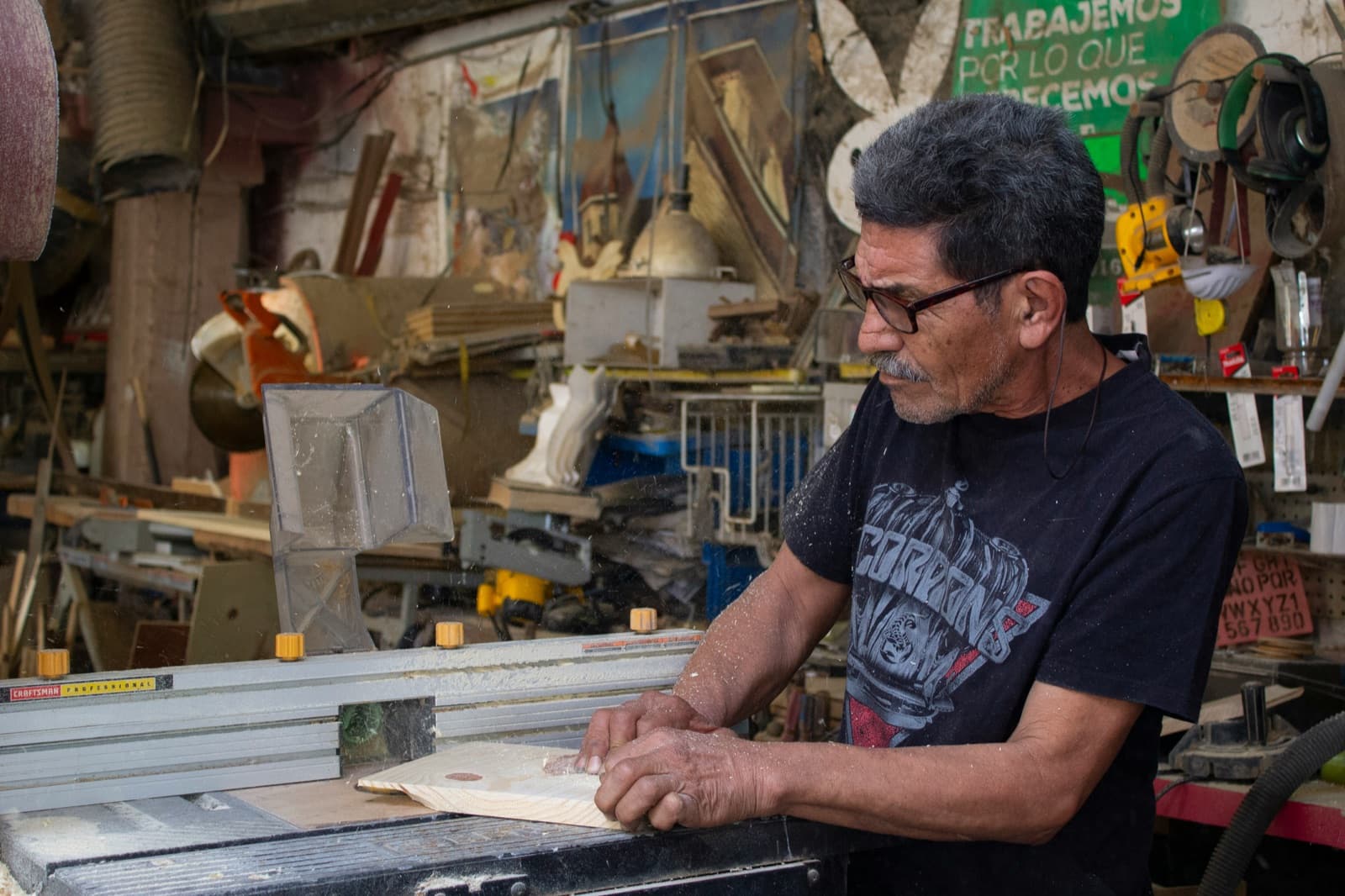 Carpintero trabajando la madera en su taller con cartel motivador