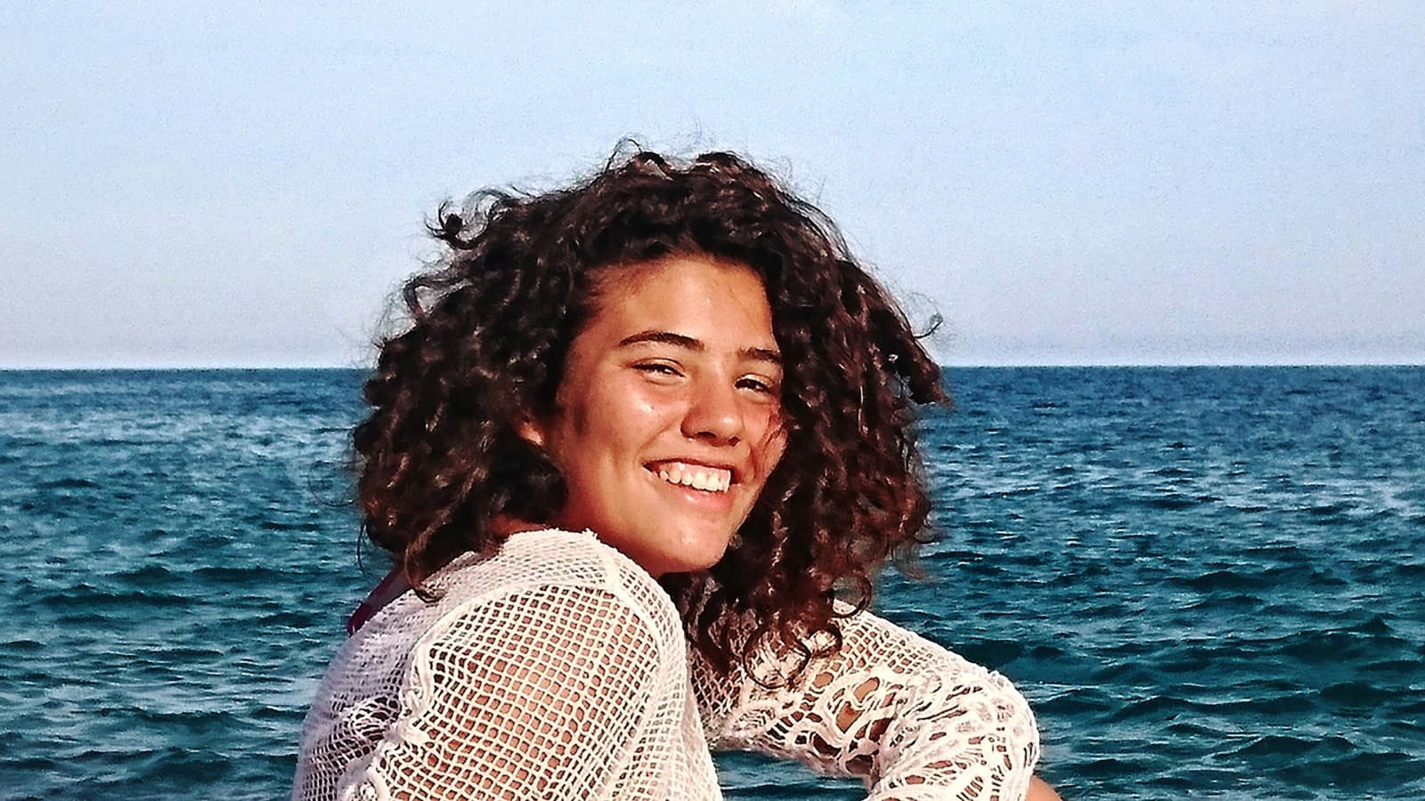 Mujer joven sonriendo junto al mar Mediterráneo